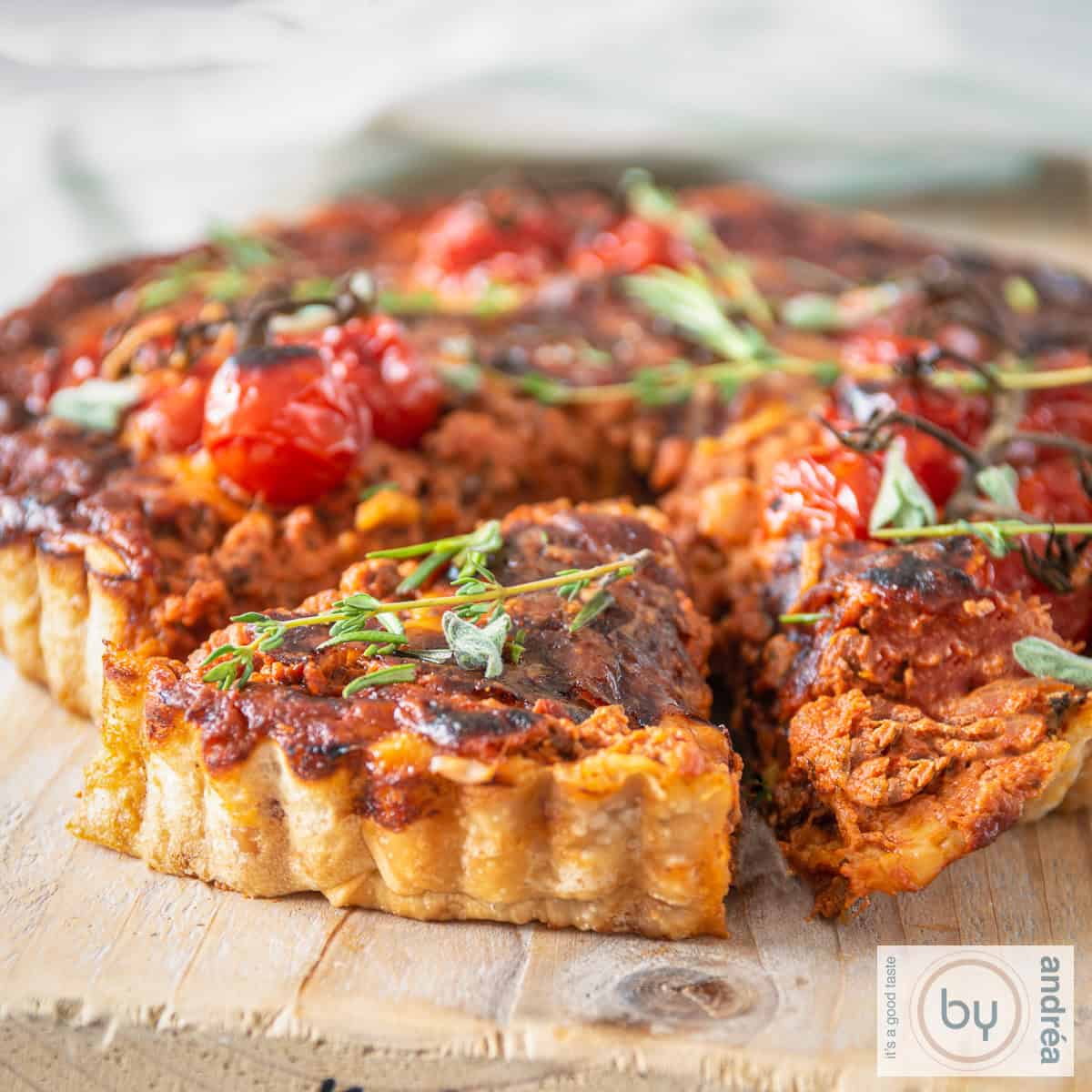 Een vierkante foto van een bolognese quiche, een punt eruit gesneden.