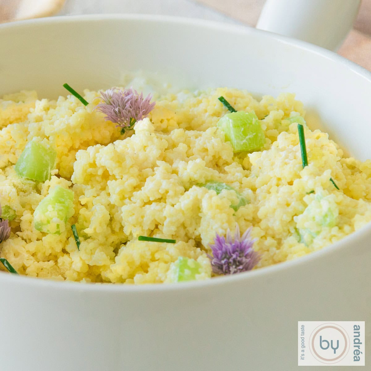 Een witte schaal met couscous salade met bieslook en komkommer