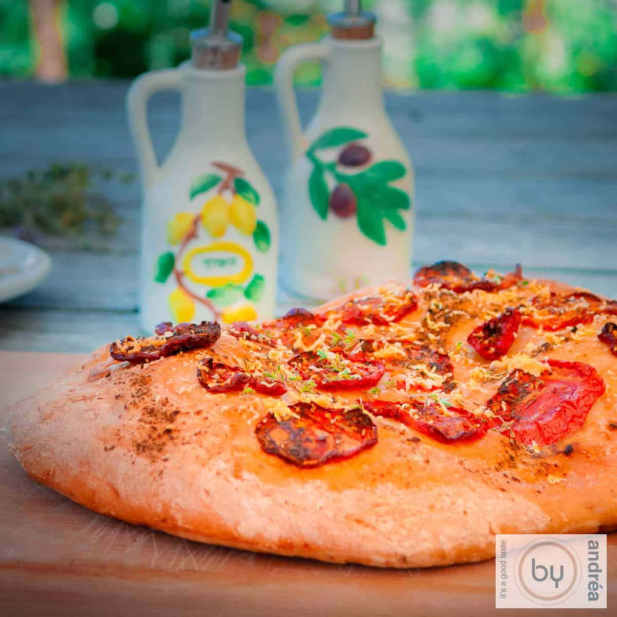 Een vierkante foto met focaccia met tomaat, italiaanse kruiden en parmezaanse kaas