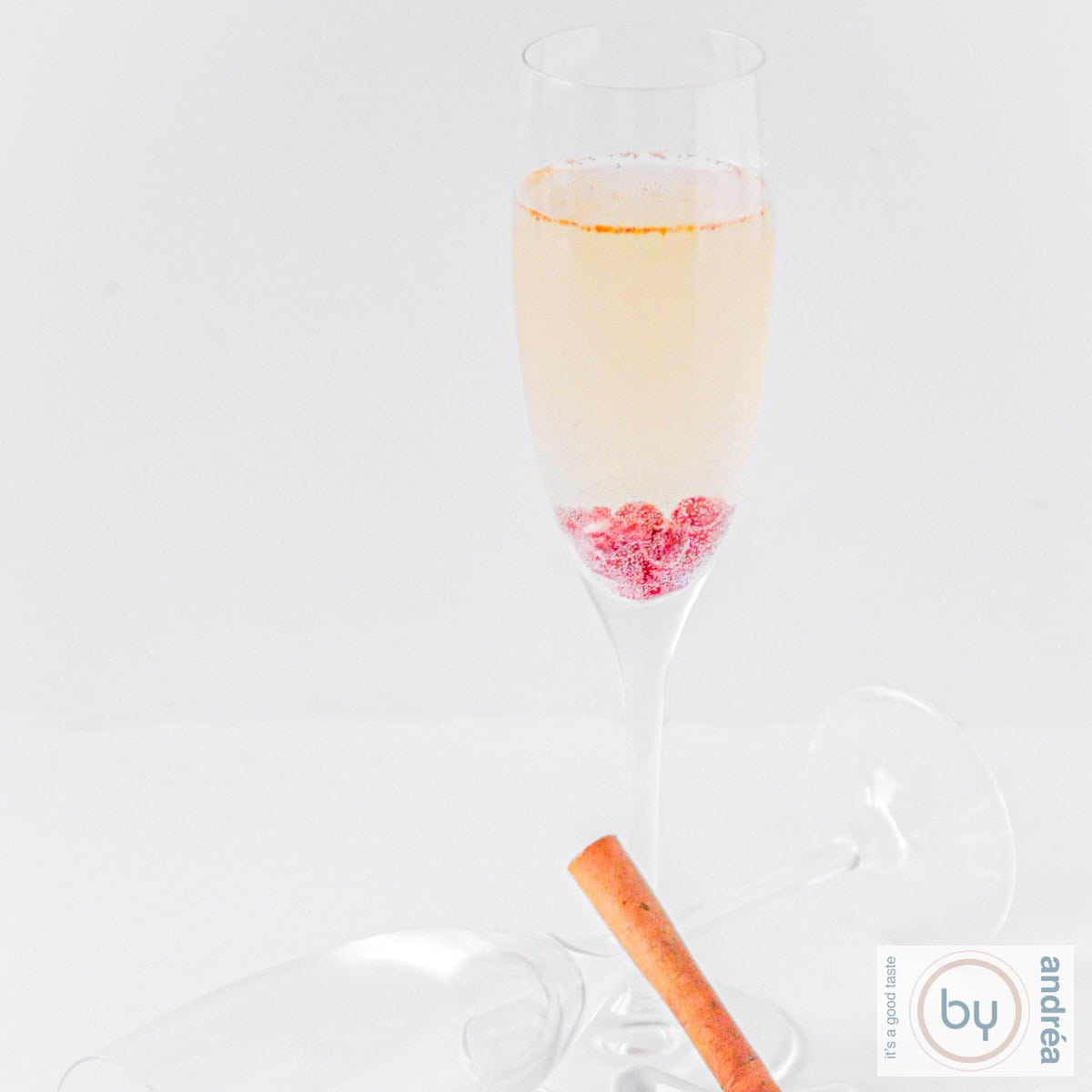 Een vierkante foto met een granaatappel prosecco coktail op een witte ondergrond