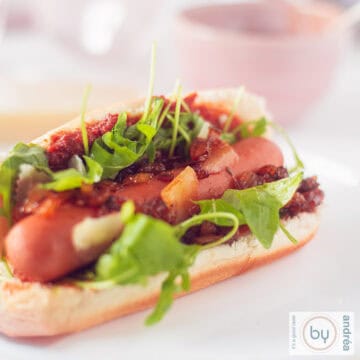 Een broodje met een hotdog en topping