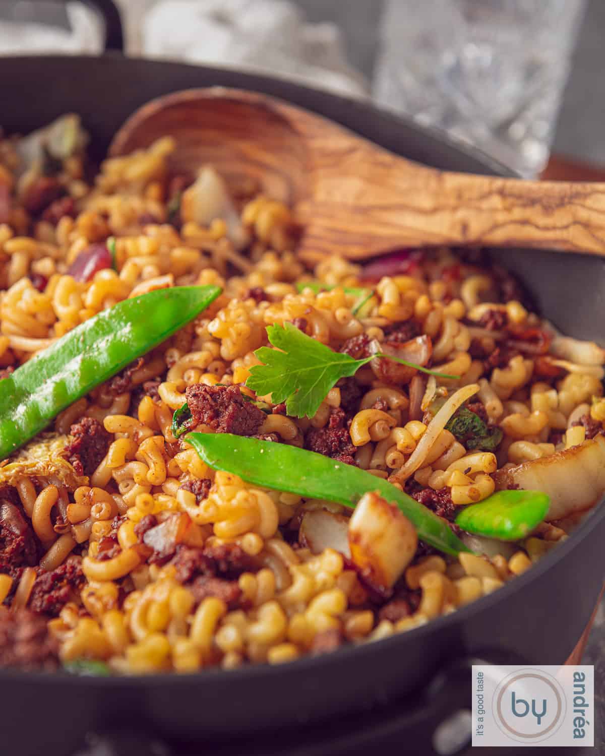 Een deel van een hapjespan gevuld met Indische macaroni met gehakt en groenten.