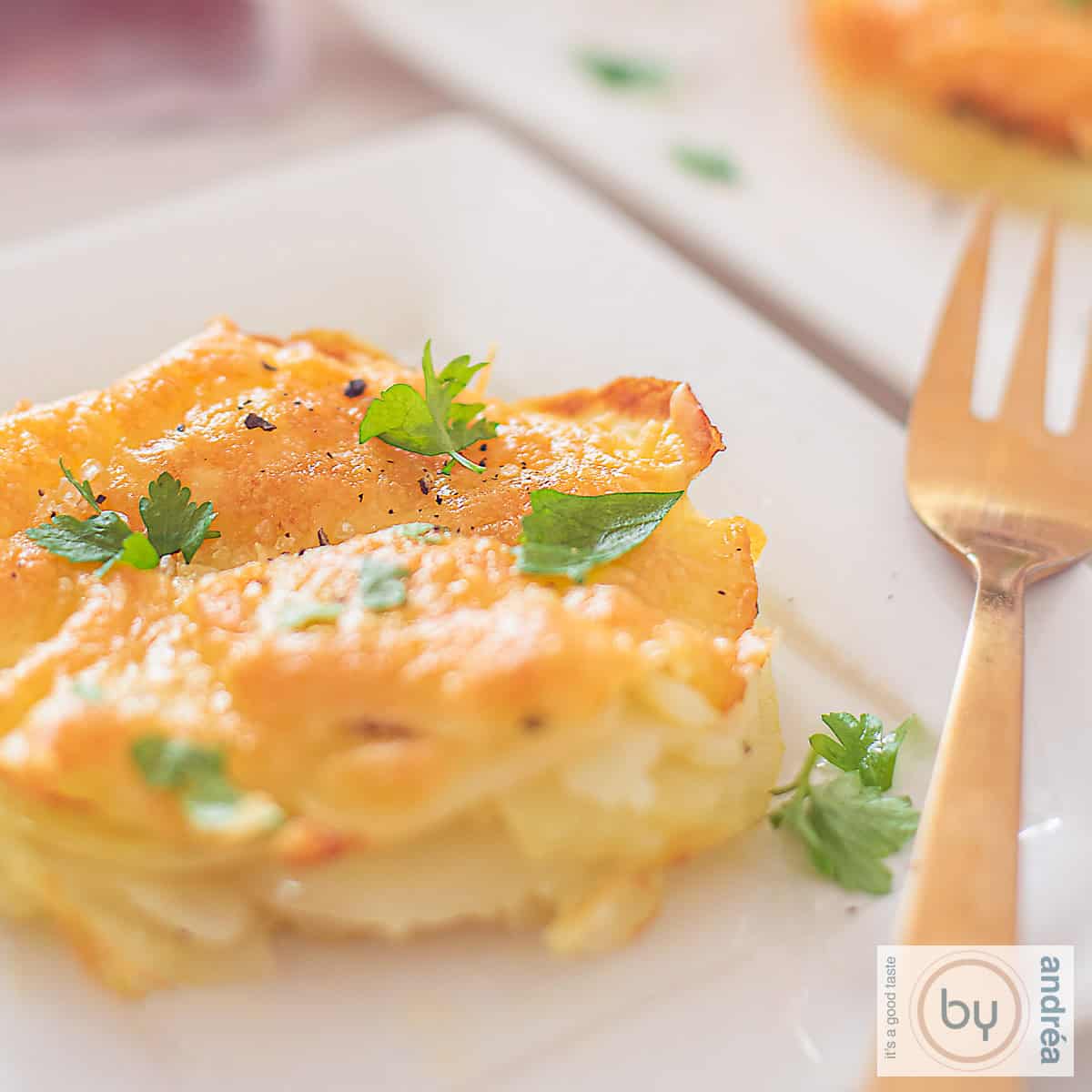 Een vierkante foto met een portie aardappelgratin.