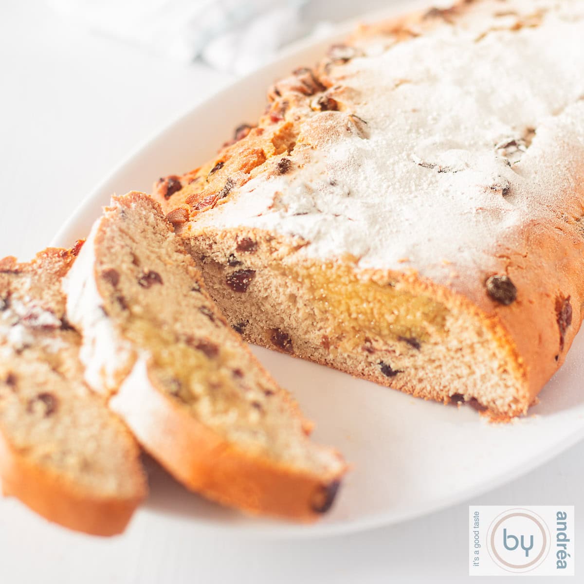 Een kerststol op een witte schaal, twee stukken eraf gesneden