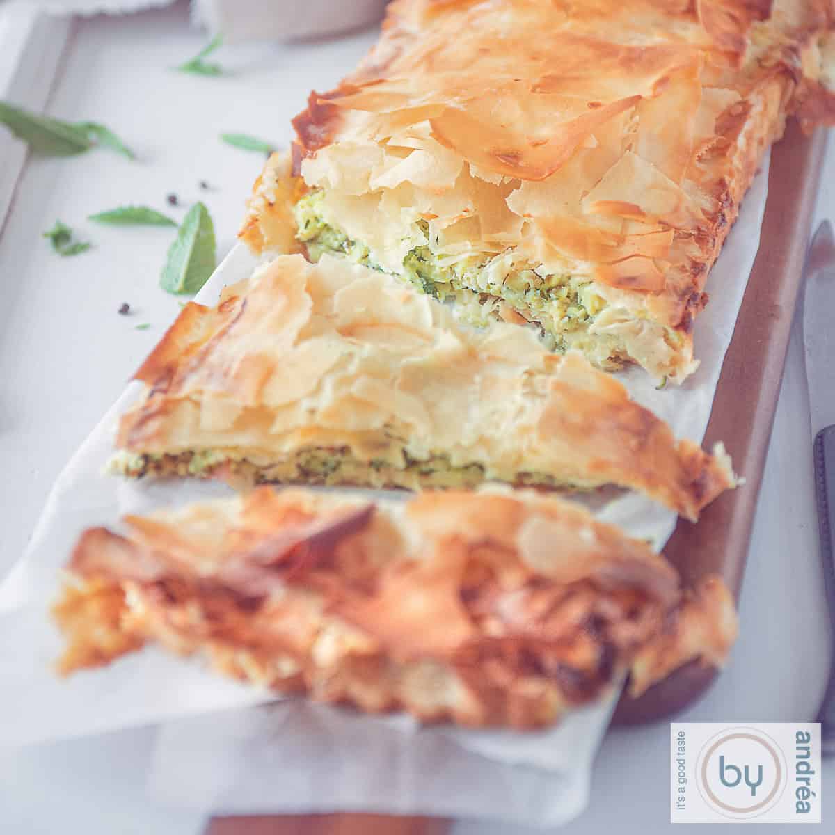 Een vierkante foto met een kolokithopita quiche met courgette.