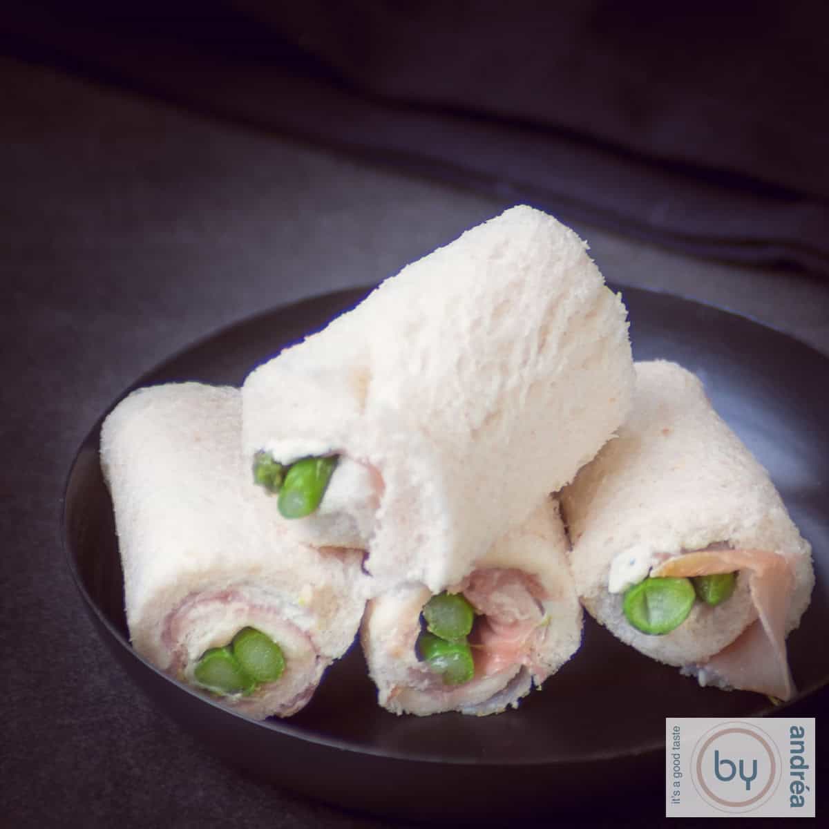 Vierkante foto met vier luxe asperge rollups met ham.