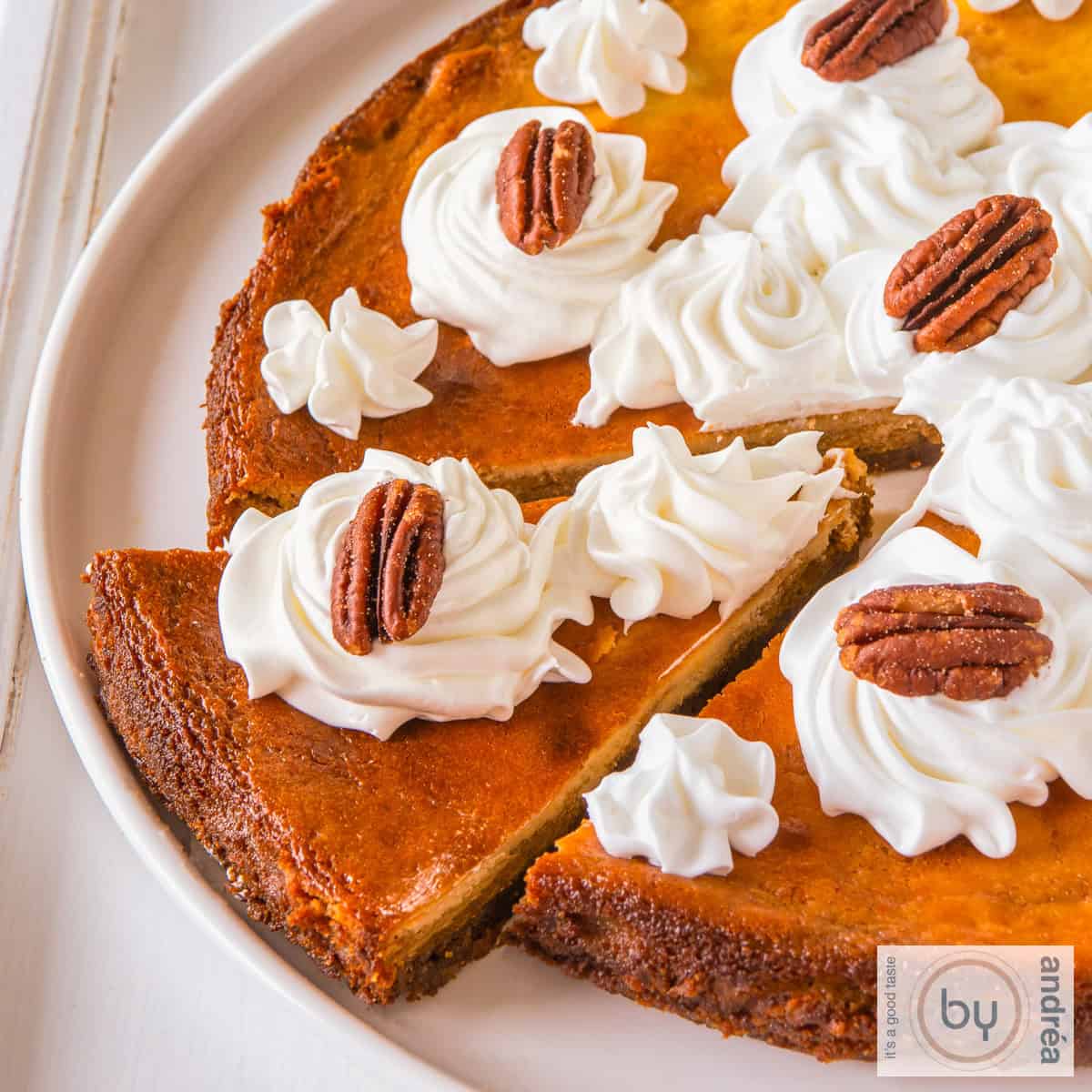 Een vierkante foto van een deel van een pompoen cheesecake waar een stuk uit is gesneden
