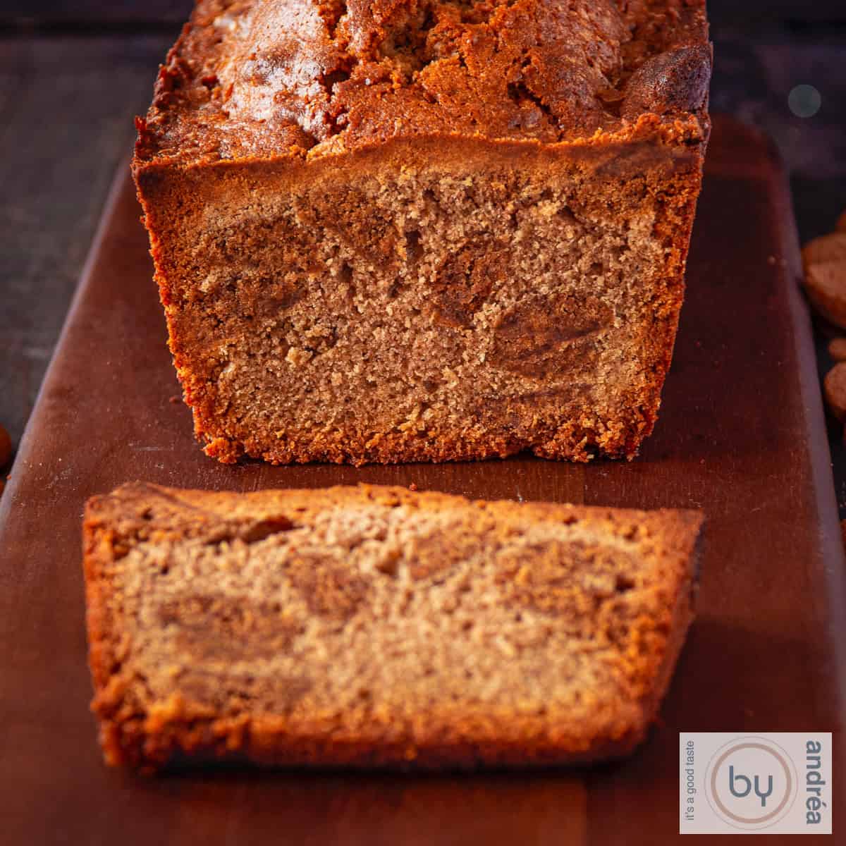 Een vierkante foto met een kruidnoten cake op een houten plank