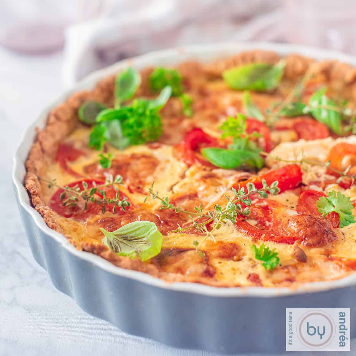 Een vierkante foto met een quiche met tomaat, mosterd en brie