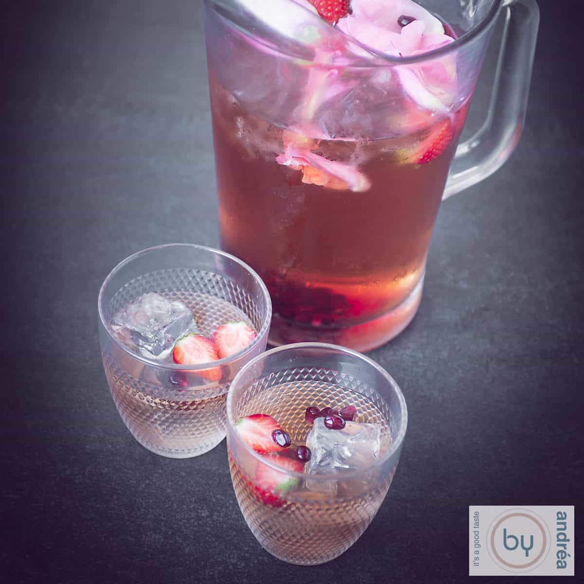 Een vierkante foto met twee glazen rozenijsthee en een grote kan