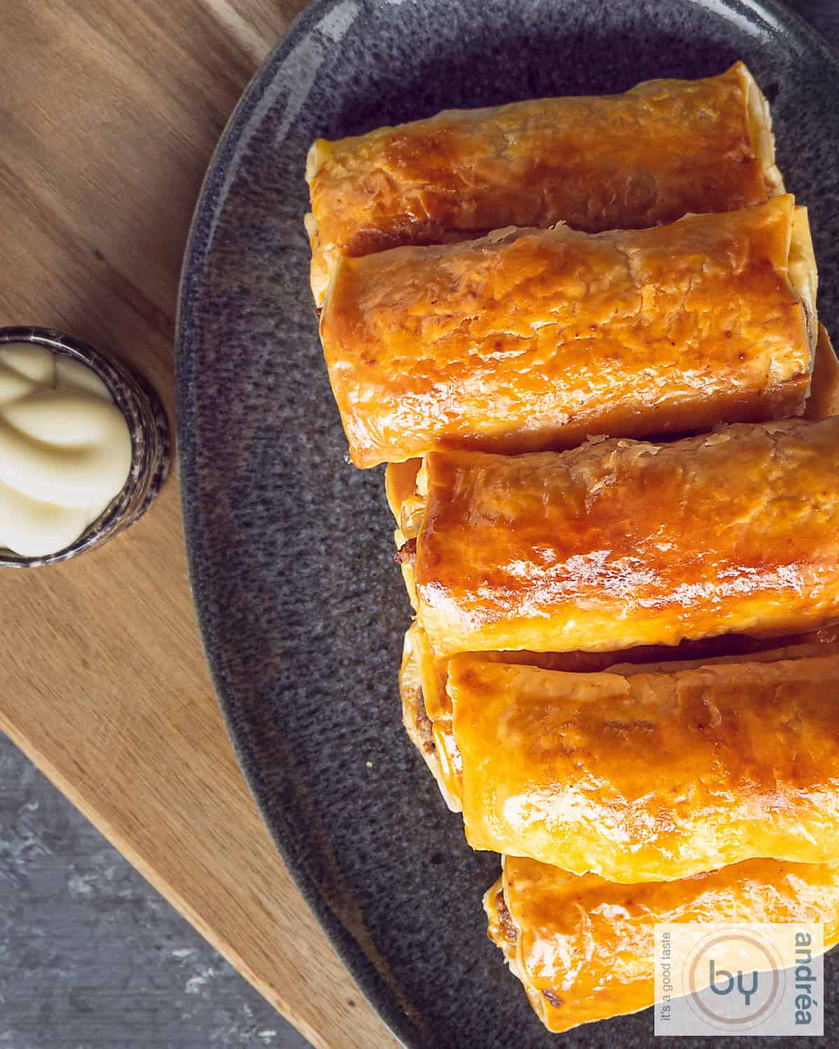 Foto van bovenaf van een grijze schaal met een stapel saucijzenbroodjes en een schaaltje mayo