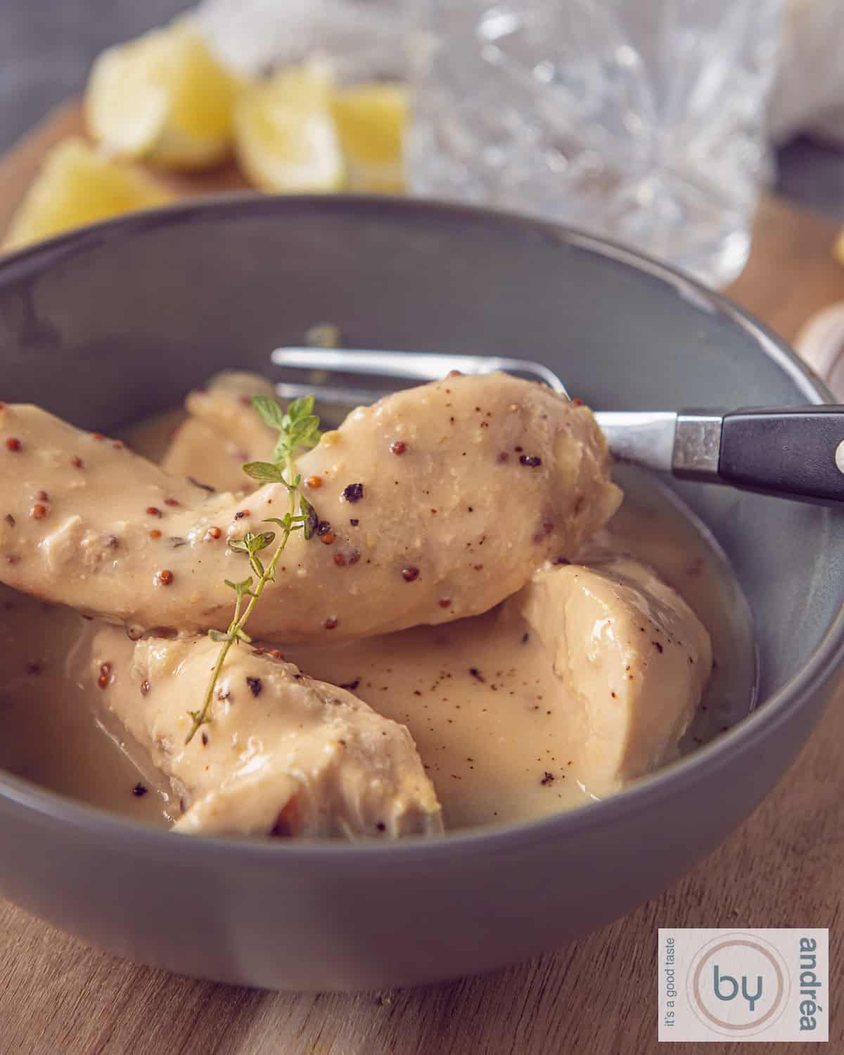 Een kom met kipfilet in een grijze kom overgoten met mosterdsaus.