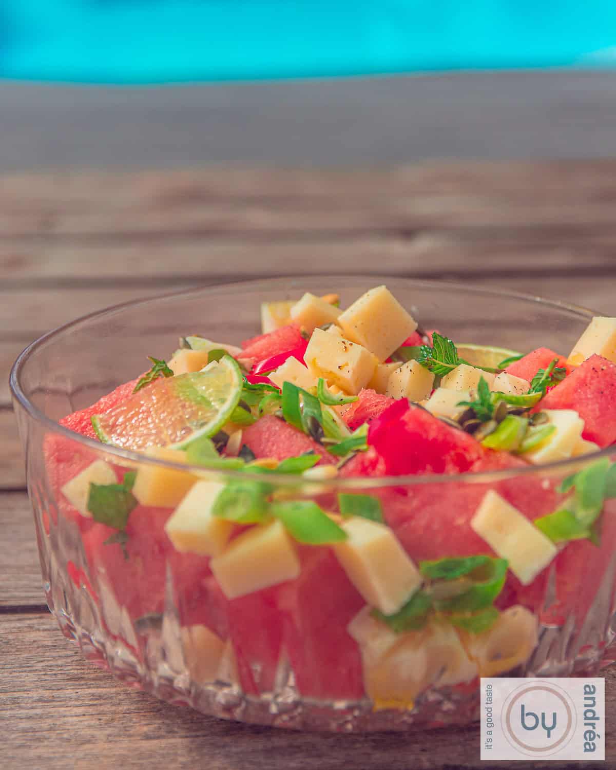 Een glazen schaal met geitenkaasblokjes, watermeloen, lente ui en limoen. Een zomerse salade