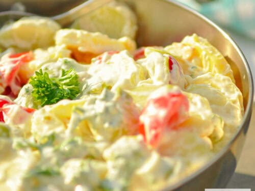 Een rvs schaal met slanke aardappelsalade op een stenen ondergrond