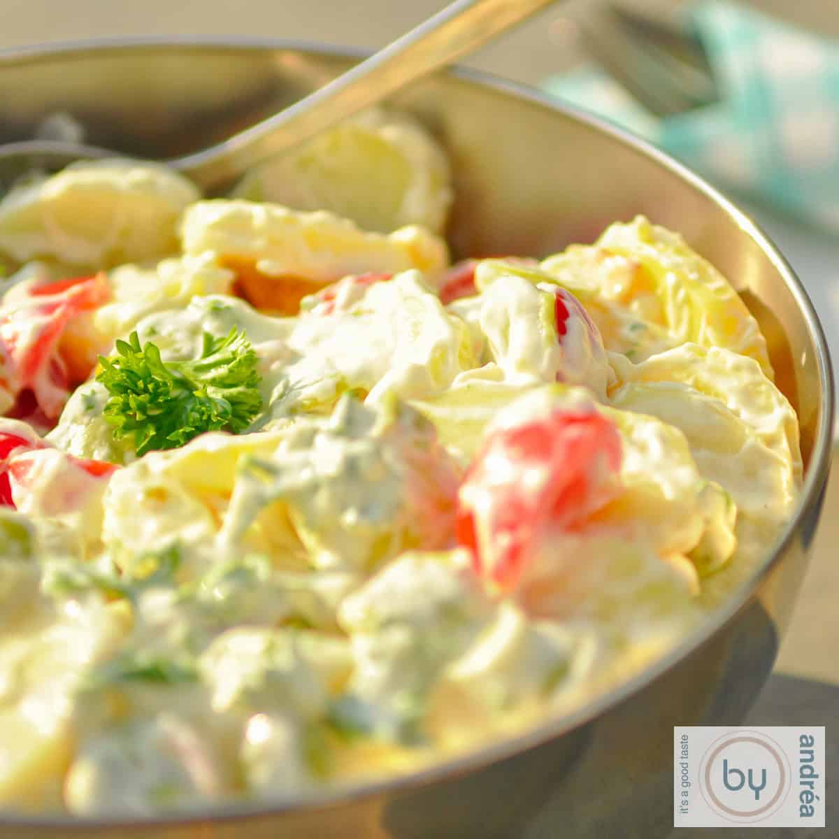 Een rvs schaal met slanke aardappelsalade op een stenen ondergrond