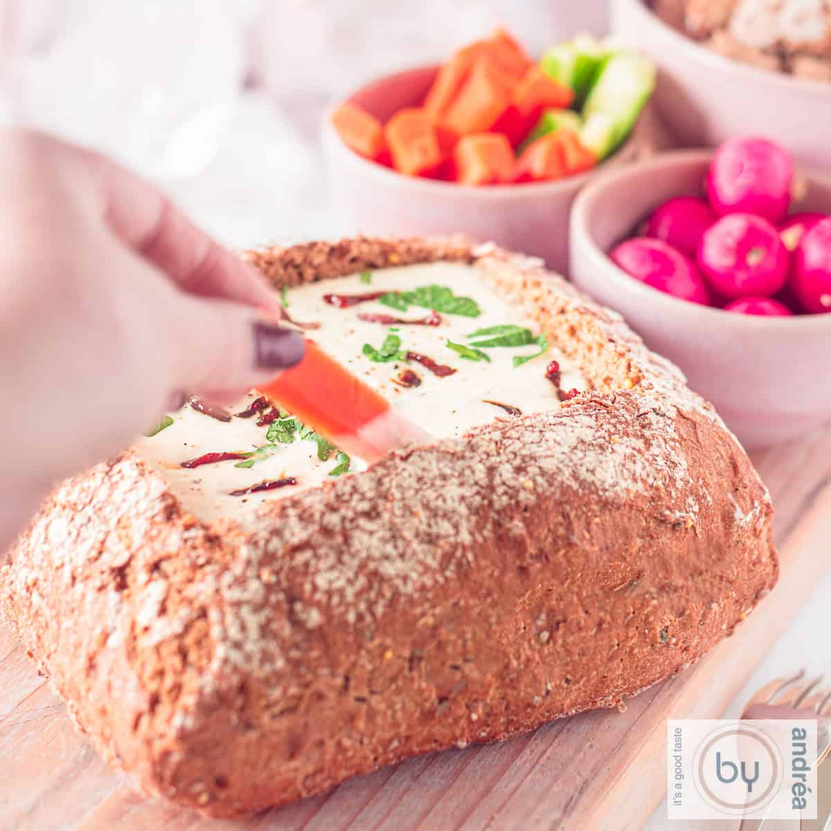 Een uitgehold brood met kaasfondue. Rauwkost eromheen om te dippen