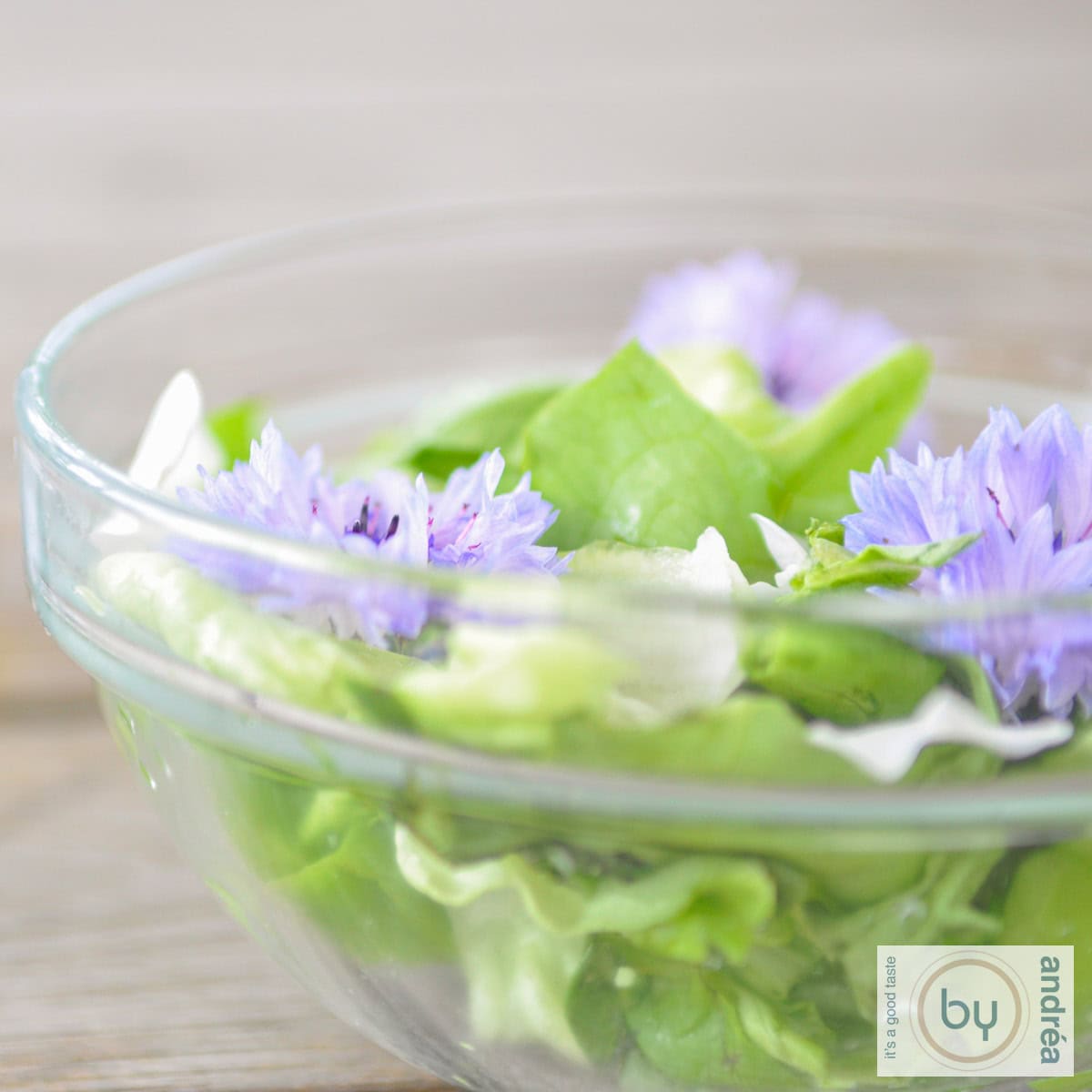 Een glazen kom met salade en eetbare bloemen