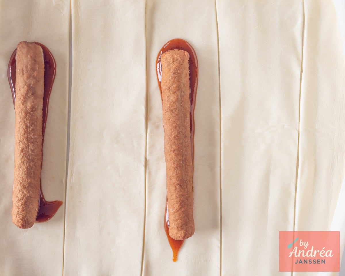 Stroken bladerdeeg met curry en een frikandel erop.