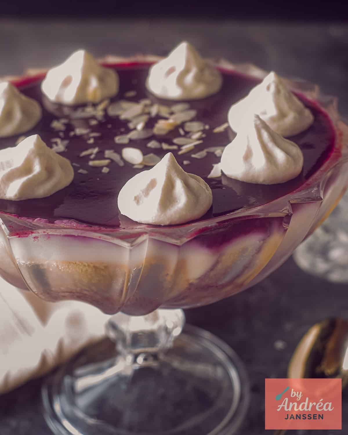 Een trifle schaal met trifle met rood fruit, custard en sherry. 