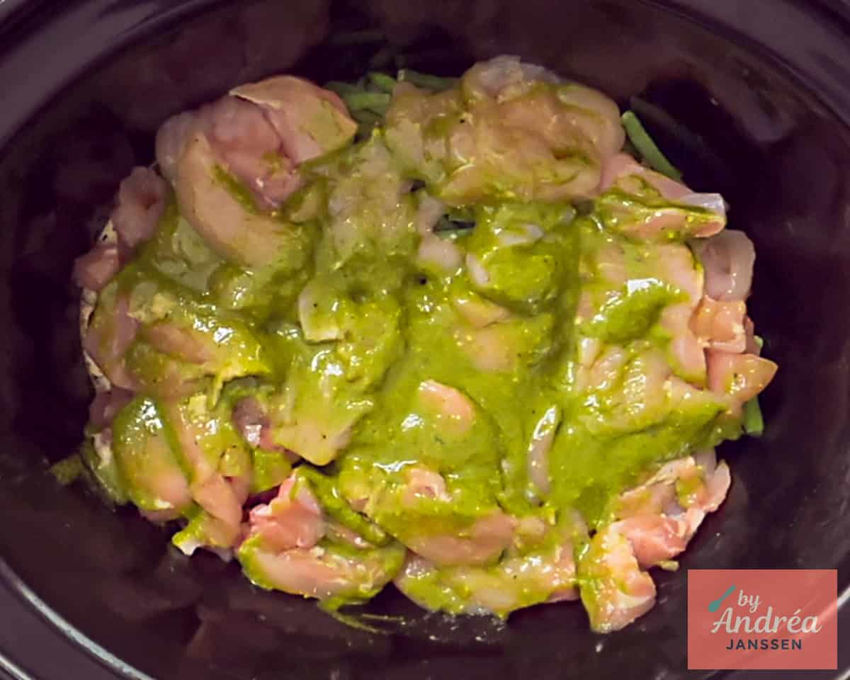 Pesto over de kip verdeeld in de slowcooker.