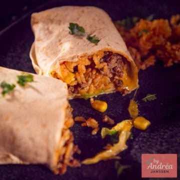 Een vierkante foto met een opengesneden burrito met een vulling van rijst, mais, gehakt, kaas, kool, tomaat en ui.
