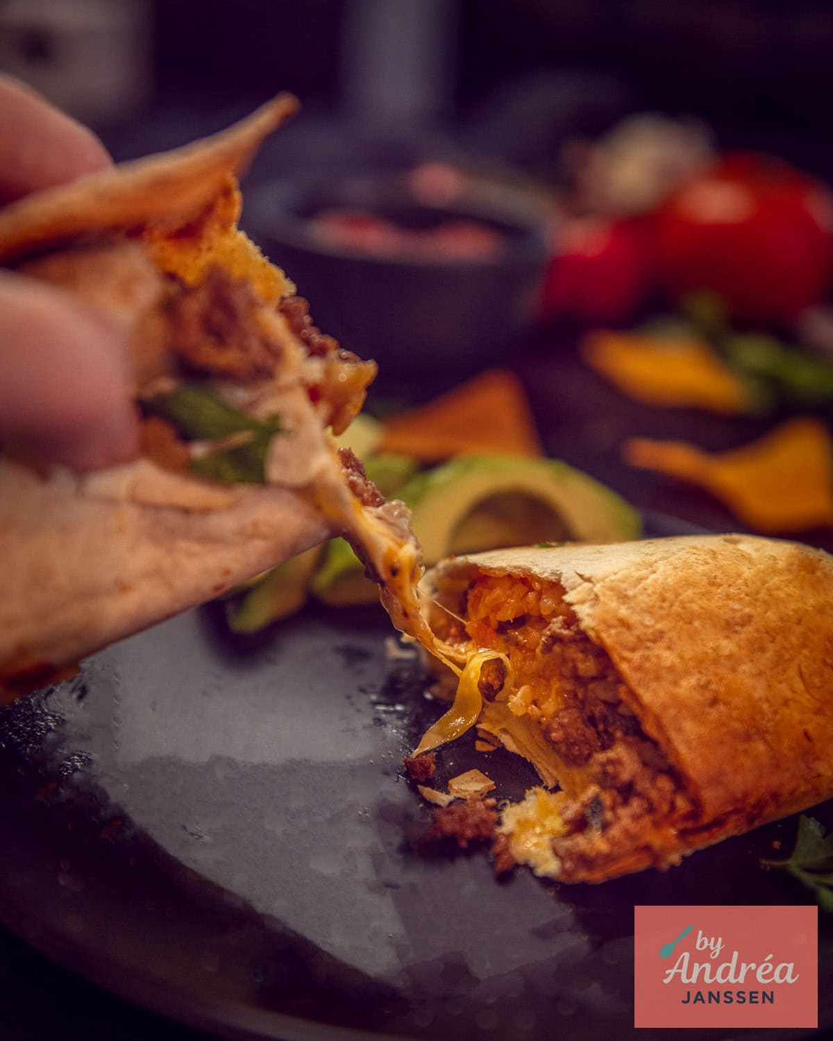 Twee helften van een burrito gevuld met gehakt en rijst die uit elkaar worden gehaald. Een cheesy string is te zien.