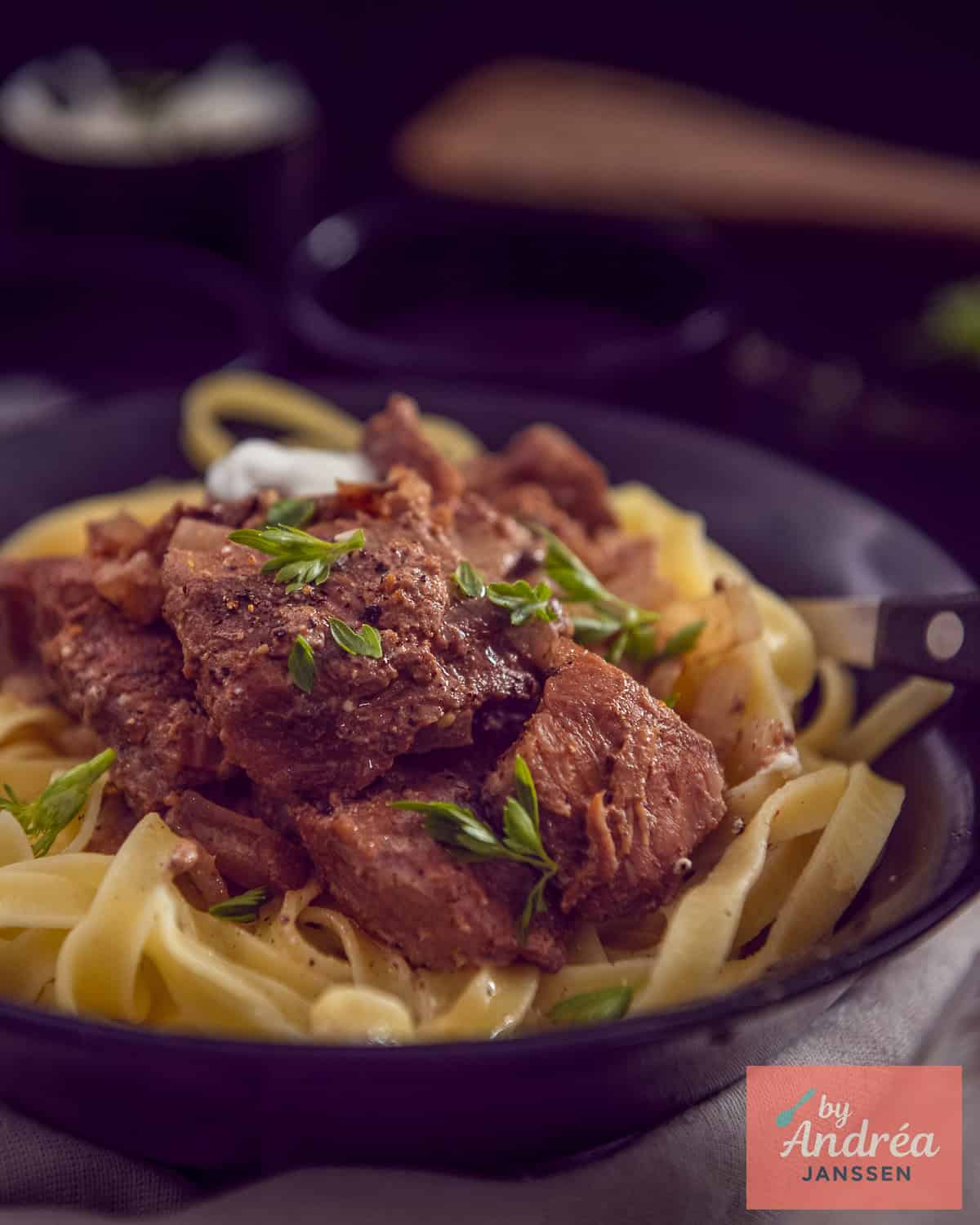 Een zwarte schaal met tagliatelle met stroganoff.