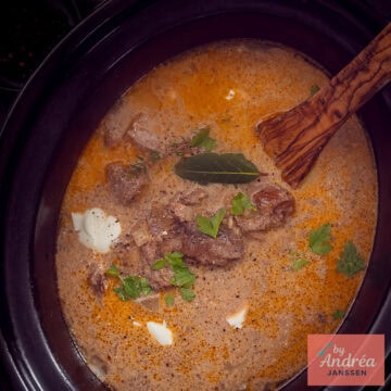 Een vierkante foto van een deel van een slowcooker gevuld met stroganoff met rundvlees.