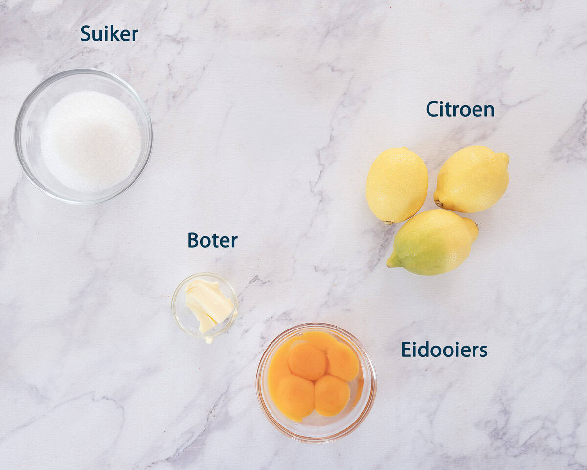 Ingredienten Zelf lemon curd maken op een wit marmeren ondergrond met tekstbeschrijving.