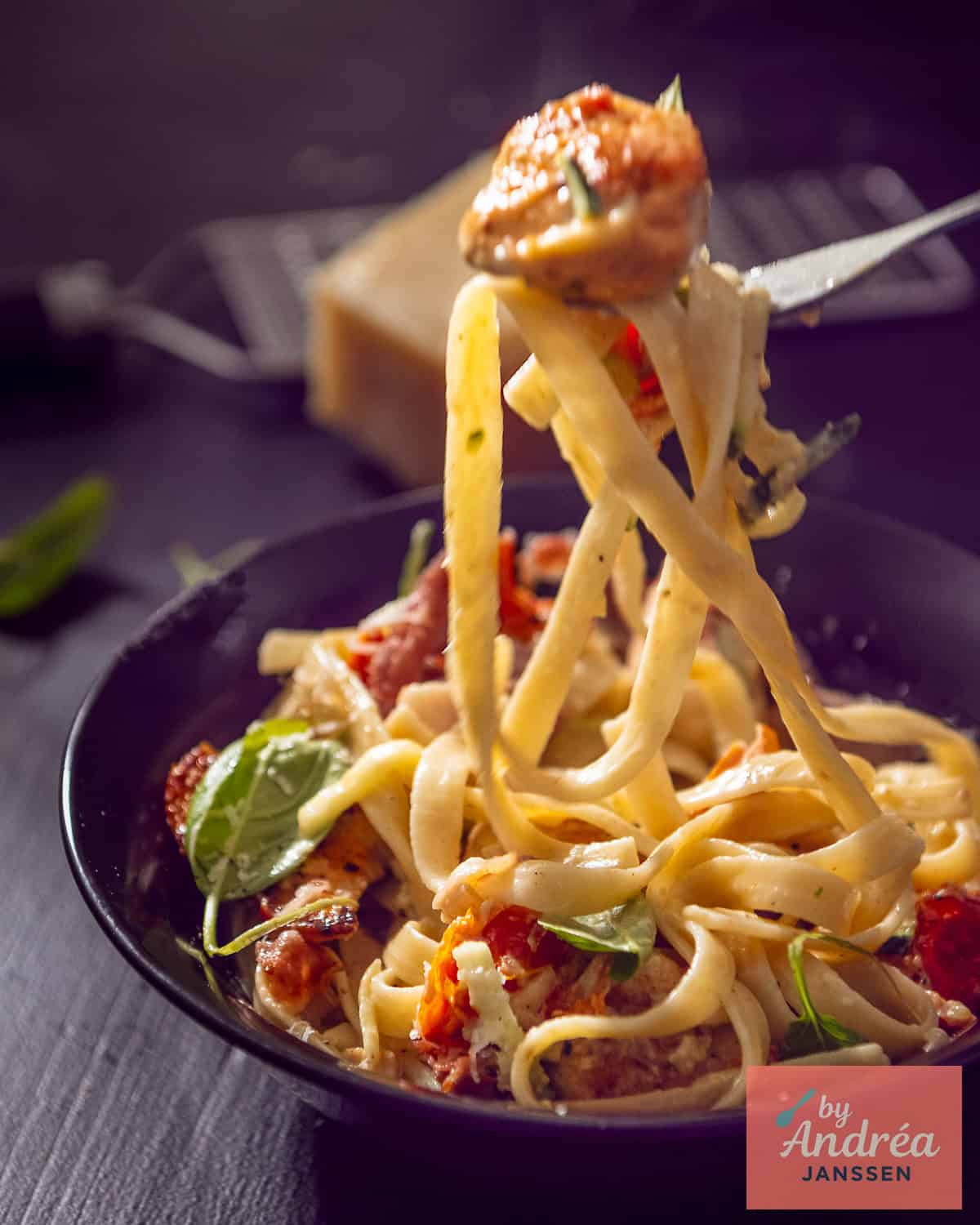 Een schaal met pasta met romige saus, kip, zongedroogde tomaten en bacon