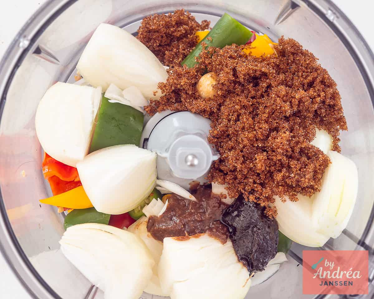 Een keukenmachine met allerlei ingredienten voor sambal badjak