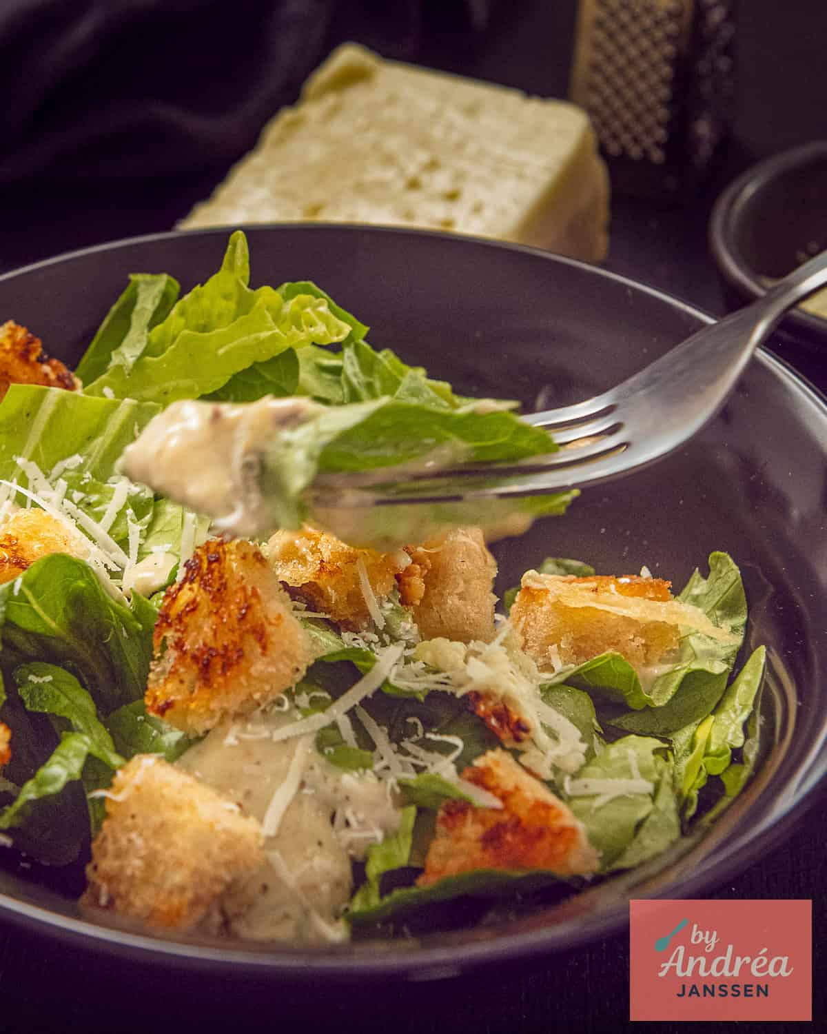 Een vork neemt een schep van de Caesar salade met croutons, kaas en dressing.