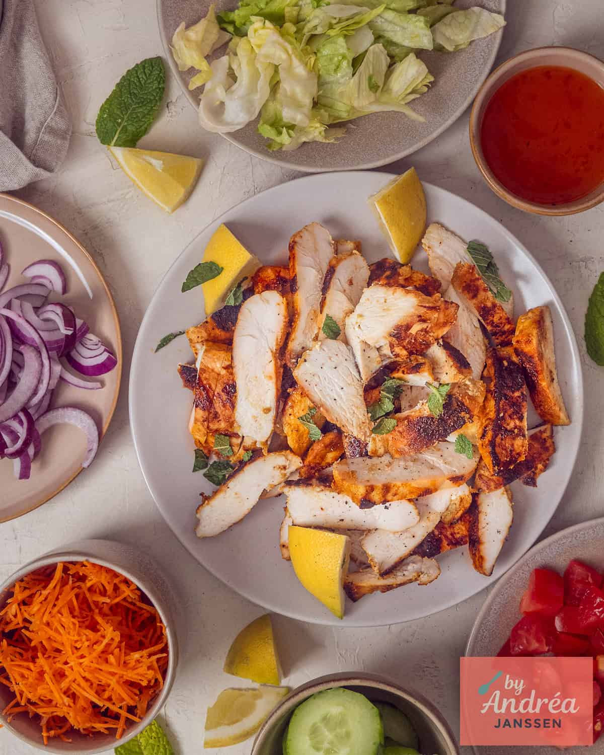 Overzicht van kipshoarma van de BBQ met alle toppings: ijsbergsla, rode ui, geraspte wortel, tomaat, komkommer en chilisaus