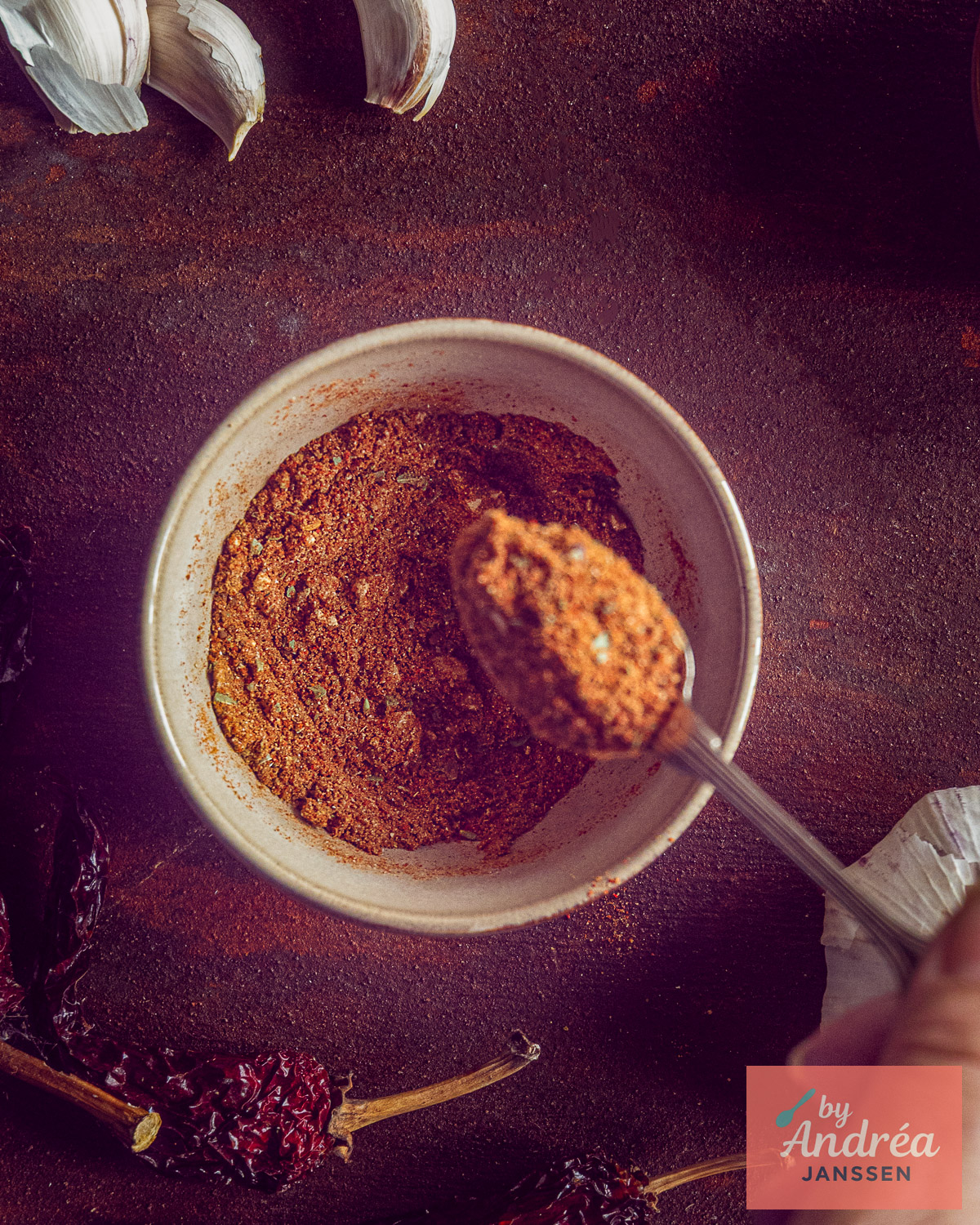 Kom met zelfgemaakte chili con carne kruidenmix van bovenaf, met een volle lepel, knoflook en gedroogde chilipepers.