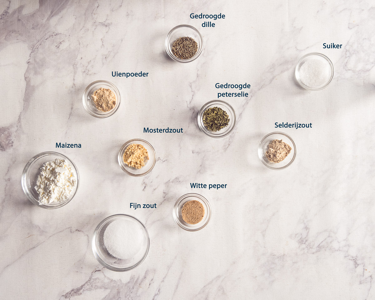 Ingrediënten voor zelfgemaakte viskruiden: fijn zout, maïzena, selderijzout, mosterdpoeder, uienpoeder, suiker, witte peper, peterselie en dille