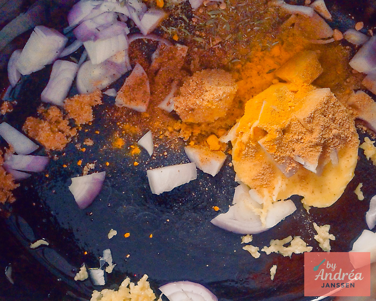 Gesneden ui en knoflook met boter, bruine suiker en specerijen op de bodem van de slowcooker.