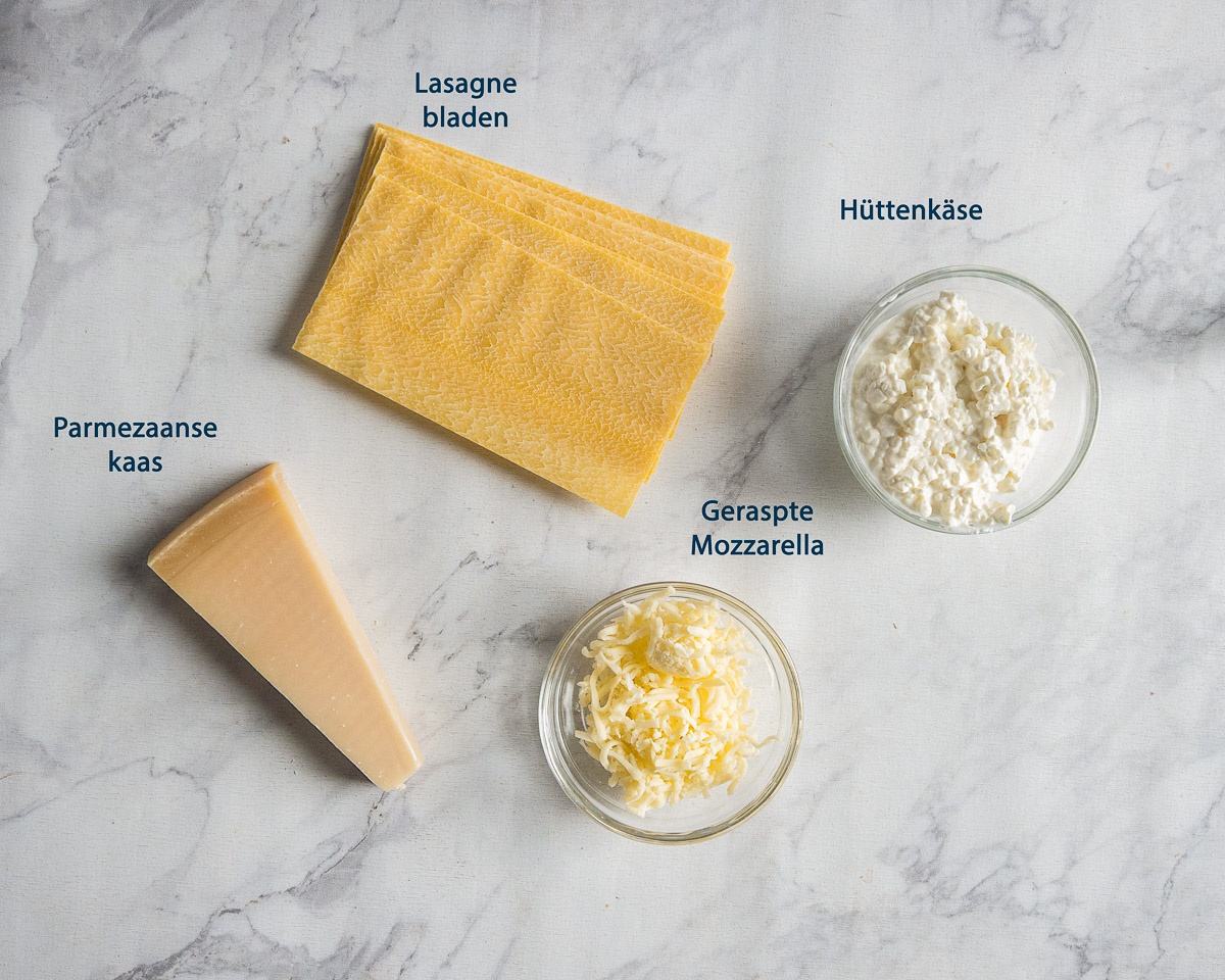 Lasagnebladen, hüttenkäse, geraspte mozzarella en een stuk Parmezaanse kaas met Nederlandse labels.