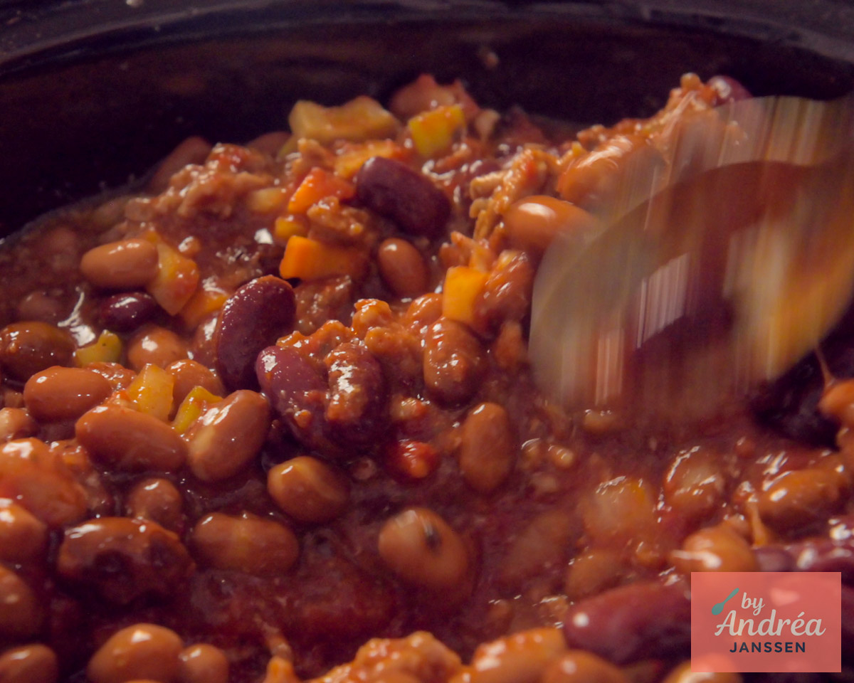 Dikke chili con carne met gehakt, bruine bonen, kidneybonen en groenten wordt geroerd in de slowcooker