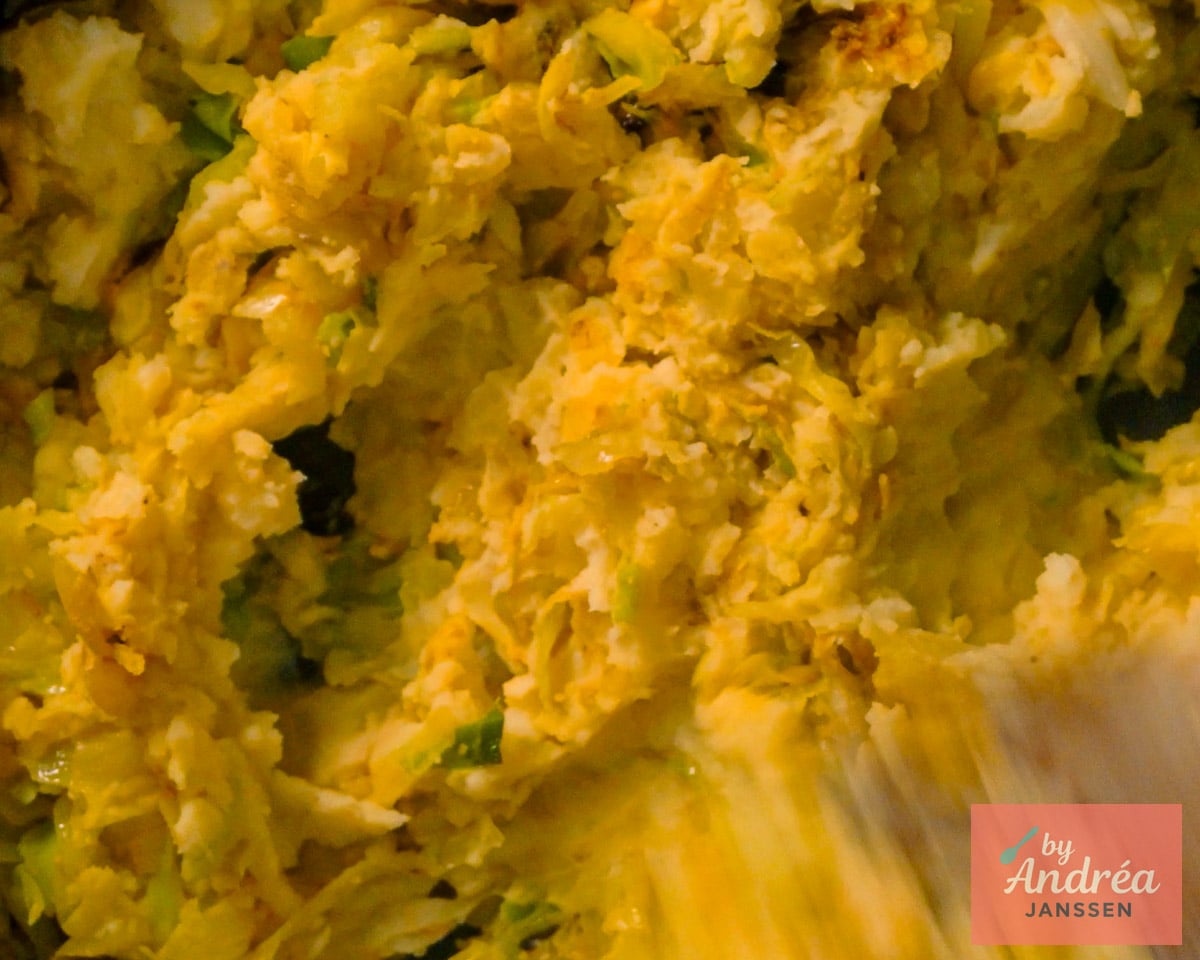Aardappelpuree wordt in de pan gemengd met gebakken spitskool en kerrie tot een grove stamppot.